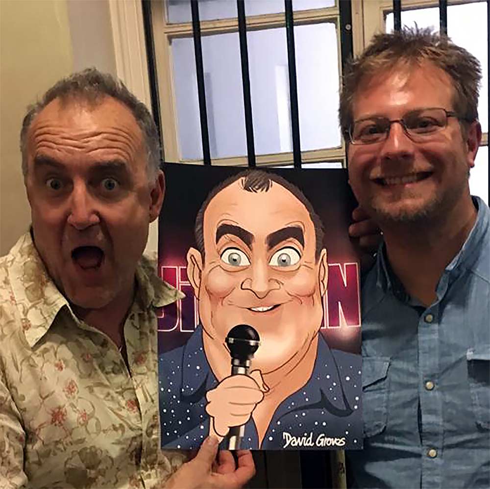 Jimeoin holding a caricature of himself